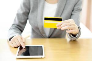 Close-up woman's hands holding a credit card and using tablet pc photo