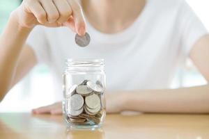 Woman hands with coins in glass jar, close up photo