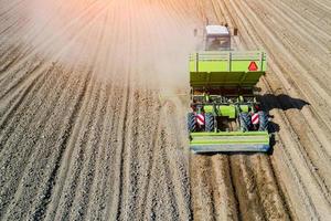 A farmer and tractor in the field planting potatoes in the fertile farm fields. Aerial view. photo