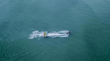 Inflatable banana boat with tourists in blue calm sea. Group of people riding banana boat. Speeding away. photo