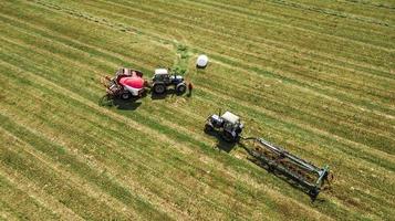 tractor recoge heno de la vista de campo desde el dron foto