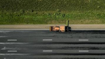 el tractor corta el borde de la carretera a lo largo de la vista aérea de la carretera foto