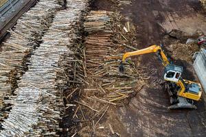 a loader loads logs at a wood processing factory from above from a drone photo