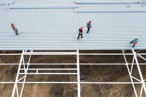 los trabajadores instalan el techo de un edificio moderno. vista superior desde un dron. foto