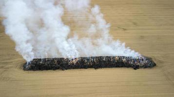 Aerial view of burnt land in the field after fire with ash and smoke photo