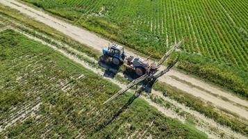 Aerial view of agricultural sprayer working on the green field on a sunny day photo