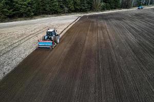 a tractor plows a field in the spring aerial view from a drone photo