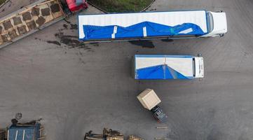 el montacargas está poniendo carga desde el almacén hasta el camión al aire libre. aéreo. vista superior foto