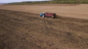 tractor scatters manure on the field aerial photography from a drone photo