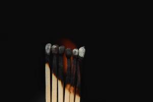 Burning matches on black background. matchsticks on fire in row of burning is sequence while one match stay down from burning to avoid fire connecting against black background photo