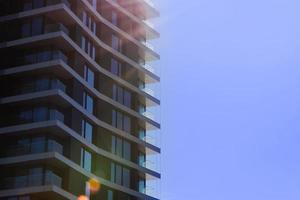 Fragment of modern multi-storey residential building against blue sky. Close-up. Background for ad or banner. Copy space. modern housing. sale of apartments. photo