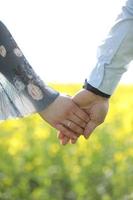 couple in love hold hands in green field in summer. close up photo