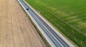 Aerial view of traffic on two lane road through countryside and cultivated fields