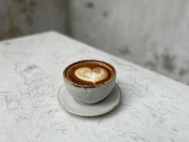 Heart latte art on coffee cup on wooden table photo