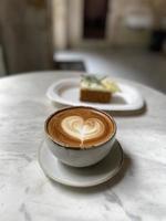 Heart latte art on coffee cup on wooden table photo