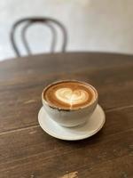 Heart latte art on coffee cup on wooden table photo