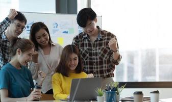 Asian creative people in modern office A new generation of business people are working with successful laptops, tablets, smartphones, notebooks. photo