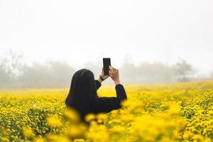 Relax solo travel adult woman on winter in blooming yellow chrysanthemum field. photo