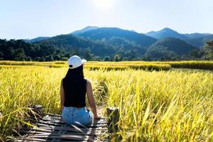 la mujer adulta que viaja sola se relaja en el campo de arroz. foto