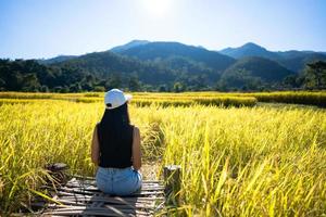 la mujer adulta que viaja sola se relaja en el campo de arroz. foto