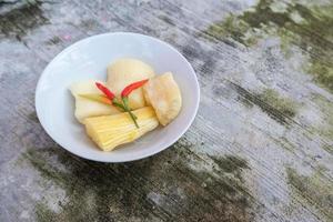 Boiled cassava is better than fried cassava, cassava in white bowl with shadow of leaves, isolated on concrete floor photo