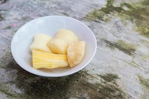 Boiled cassava is better than fried cassava, cassava in white bowl with shadow of leaves, isolated on concrete floor photo