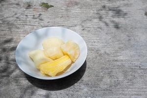 Boiled cassava is better than fried cassava, cassava in white bowl with shadow of leaves, isolated on concrete floor photo