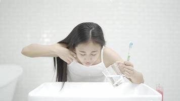 jovem mulher limpando os dentes com uma escova de dentes no banheiro em frente ao espelho admirando seu reflexo video
