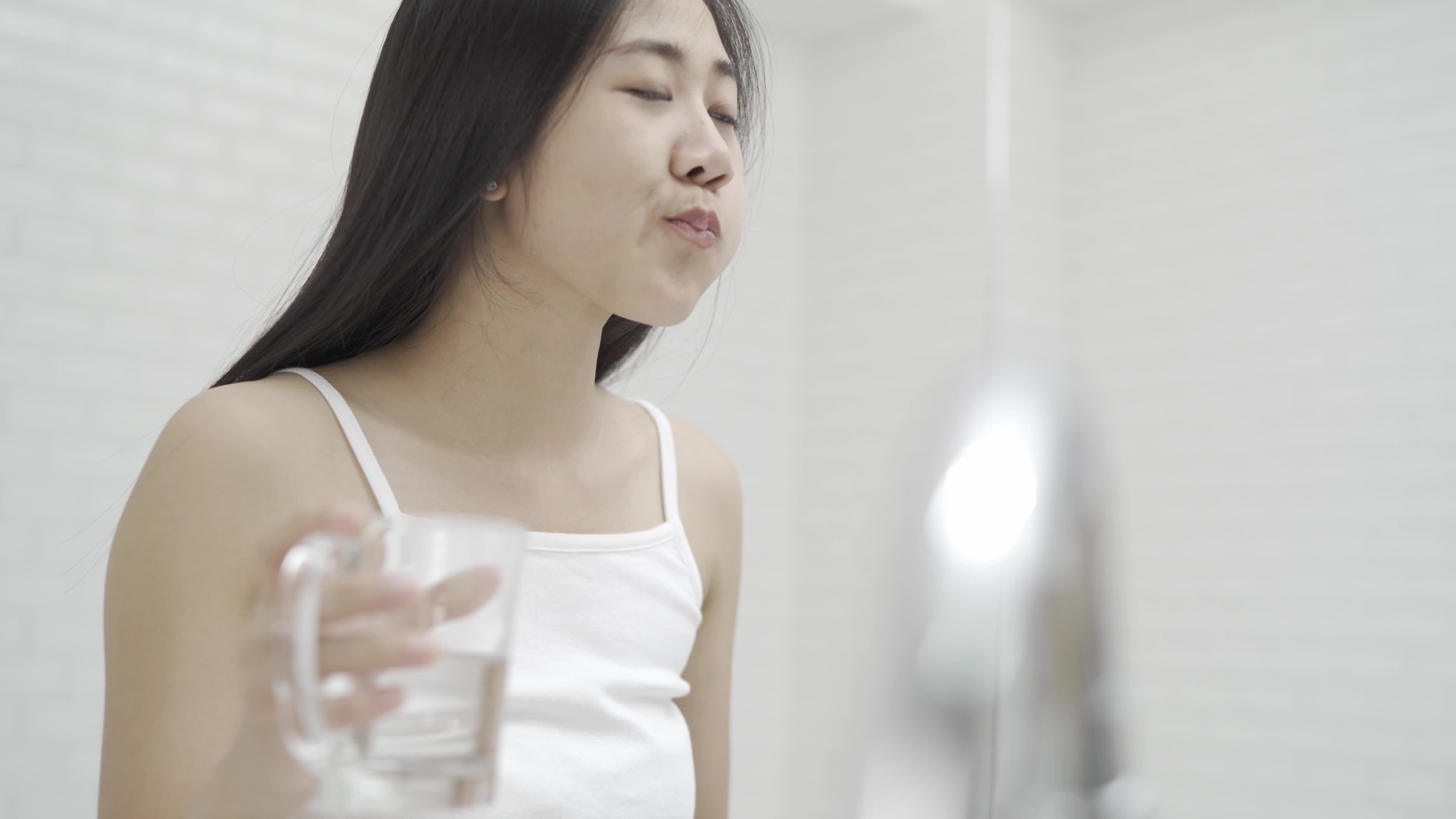 A cute Asian woman brushing her teeth and gargling in front of the mirror after waking up every morning. pic