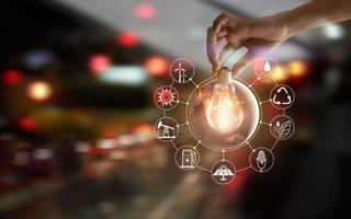 Hand holding light bulb  show the world's consumtion with icons energy sources for renewable, sustainable development. Ecology and enviroment concept. Elements of this image furnished by NASA. photo