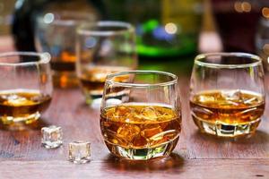 whiskey drinks with ice on wooden background photo