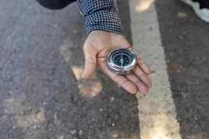 On the road a traveler's hand is looking for directions from a compass. photo