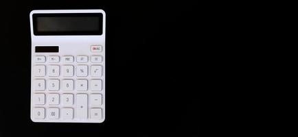 white calculator on a black background with copyspace. Flatlay, Top view, Banner background photo