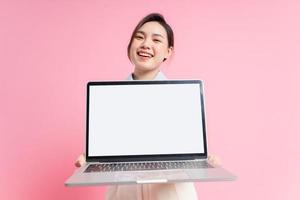 imagen de una joven mujer de negocios asiática sosteniendo una laptop con fondo rosa