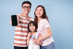 Image of young Asian family using smartphone on blue background photo