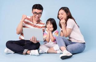 Image of young Asian family using laptop on blue background photo