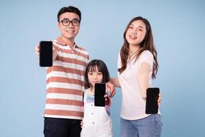 imagen de una joven familia asiática usando un teléfono inteligente con fondo azul foto