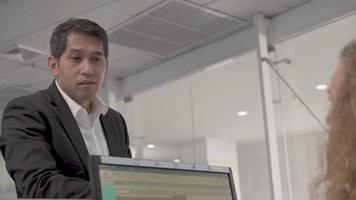 Asian businessman receiving passport and boarding pass from female airline officer at check in counter service in the airport terminal video