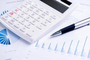 White calculator and report with chart and graph, concept of annual financial profit overview, banking and investment, copy space, macro, close up photo