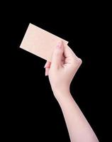 mano de niña limpia de asia joven sosteniendo una plantilla de tarjeta de papel marrón kraft en blanco aislada en fondo negro, ruta de recorte, cierre, maqueta, corte foto