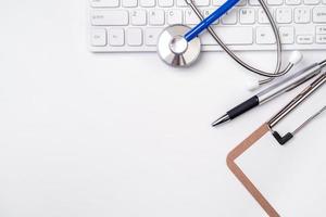 Stethoscope on computer keyboard on white background. Physician write medical case long term care treatment concept, top view, flat lay, copy space photo