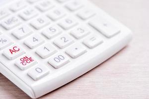 White calculator and pen on bright wooden table, analytics and statistics of financial profit, investment risk concept, copy space, macro, close up photo