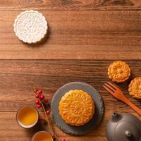 Creative Moon cake Mooncake table design - Chinese traditional pastry with tea cups on wooden background, Mid-Autumn Festival concept, top view, flat lay. photo