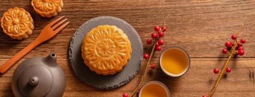 Moon cake Mooncake table setting - Chinese traditional pastry with tea cups on wooden background, Mid-Autumn Festival concept, top view, flat lay. photo