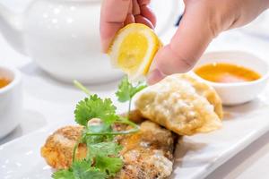 Delicious dim sum, famous cantonese food in asia - Fried fish and dumplings with lemon, sauce and tea in hong kong yumcha restaurant, close up photo