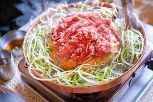 Beef barbecue bulgogi in Korean restaurant in Seoul, lifestyle fresh korean food cuisine on copper pan with sliced green onion, close up, copy space photo