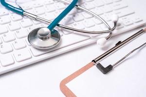 Blue stethoscope on computer keyboard on white table background. Online medical information treatment technology concept, close up, macro, copy space photo