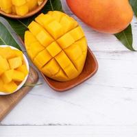 Fresh chopped mango on a tray and bright rustic wooden background. Tropical summer fruit design concept, close up, macro, copy space. photo