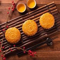 Moon cake Mooncake table setting - Chinese traditional pastry with tea cups on wooden background, Mid-Autumn Festival concept, top view, flat lay. photo