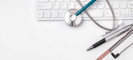 Stethoscope on keyboard on white table background. Online medical information treatment technology office concept, top view, flat lay, copy space photo